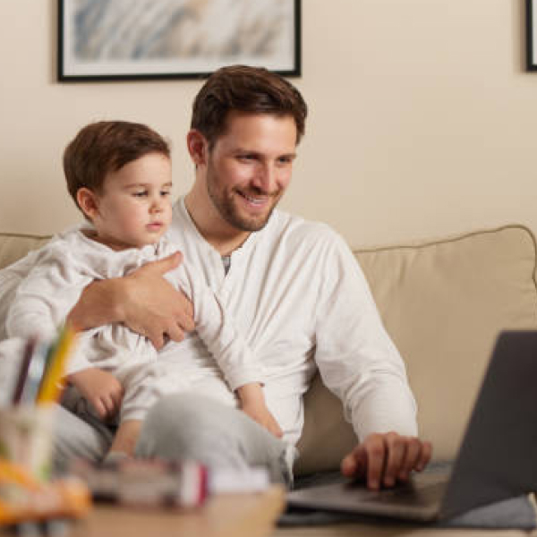 Parental Affinity Group - photo of a father and young son sitting on a couch with a laptop.